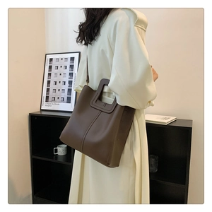 Minimalist dark brown leather bucket bag featuring unique rectangular cutout handle