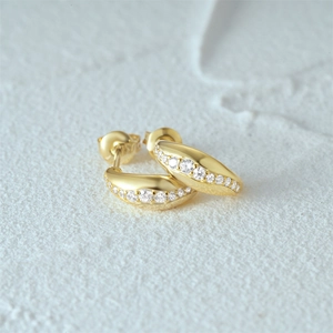 Macro view of gold-plated C-shaped earrings with inlaid round cubic zirconia stones