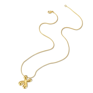 Macro detail of golden puffer X-shaped pendant with sleek snake chain texture