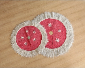 Detail of red Christmas tree skirt with plush white trim and snowflake pattern on wood floor