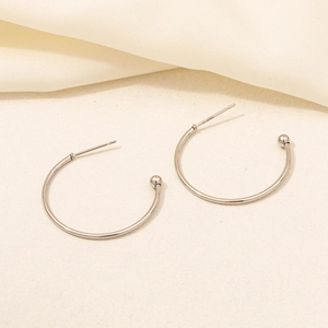 Detailed view of silver hoop earrings with round bead ends on a soft textured fabric