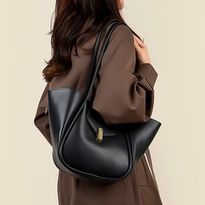 Détail du sac bandoulière en cuir noir avec fermoir en métal doré et pli géométrique