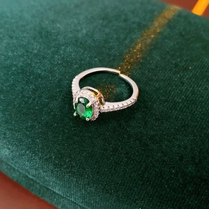 Macro detail of silver ring featuring green oval gemstone on dark velvet box
