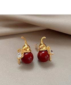 Close-up of golden gourd stud earrings with red beads and zircon on silk texture