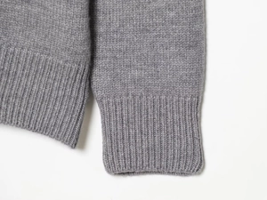 Detailed close-up of the ribbed cuff texture on this gray wool knit sweater
