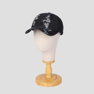Detail shot of distressed black denim baseball cap with frayed holes on crown