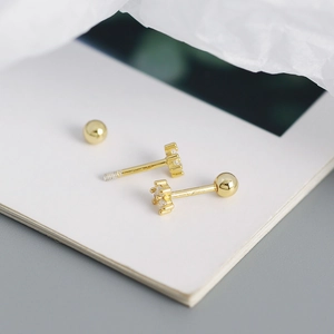 Macro detail of gold-plated mini stud earrings with clear zircon and screw-back closure