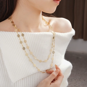 Detail of vintage French gold layered necklace featuring hollow quatrefoil clover charms