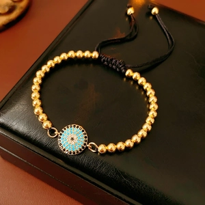 Détail du bracelet œil protecteur avec zircons bleus et perles dorées sur cuir noir