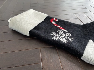Detailed knit texture of black Christmas stocking with candy cane and snowflake patterns