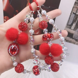 Close-up of red and white beaded phone strap with rhinestone accents and soft pom-pom