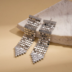 Détail de boucles d'oreilles pendantes argentées avec cristaux sur support en pierre