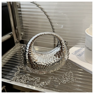 Détail du sac demi-lune en métal argenté avec texture martelée et bandoulière chaîne