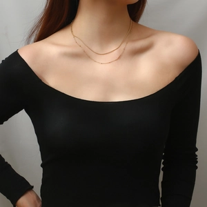 Close-up of double-layer gold necklace featuring sleek snake and bead chain on model