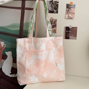 Dettaglio della borsa tote in tela tie-dye con manici verdi e motivo artistico arancione