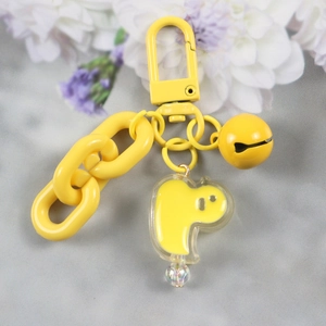 Yellow keychain set with chunky chain, bell and acrylic pendant on floral background