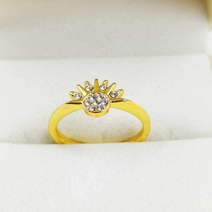 Close-up of golden sun-shaped ring with sparkling crystals on white velvet display