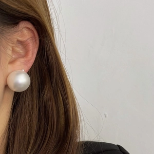 Elegant oversized white pearl stud earrings on model, minimalist vintage style jewelry
