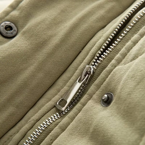 Détail macro de la fermeture éclair en métal et du tissu en toile vert olive de la veste