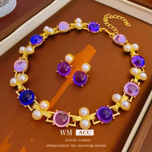 Parure bijoux vintage dorée avec pierres violettes et perles sur présentoir en cuir