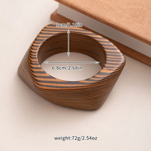 Detail view of the square wooden bangle with black and yellow stripes and dimensions