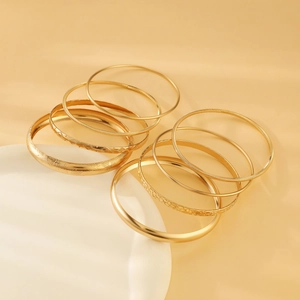 Detail of 10-piece gold alloy bangle set with diverse textured finishes on white tray