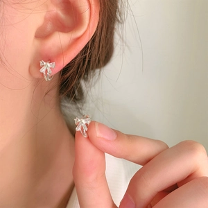 Sparkling S925 silver bow earrings with cubic zirconia stones shown on ear model