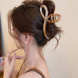 Detailed view of amber marbled acrylic hair claw clip holding a secure bun on model