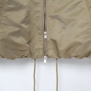 Detail of khaki jacket hem featuring silver metal zipper and adjustable drawstring closure
