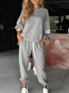 Detail of gray knitted two-piece set featuring drawstring waistband and sleeve patch
