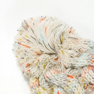 Macro detail of mixed color knitted beanie with plush faux fur pompom and textured yarn