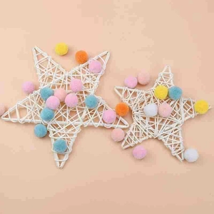 Handgefertigte weiße Rattan-Sterne mit bunten Pompons für festliche Weihnachtsdekoration