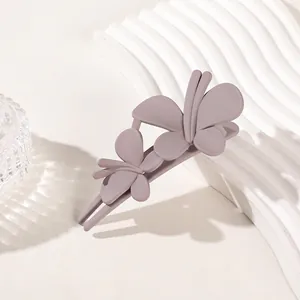 Detailed view of a matte purple double butterfly hair clip on a wavy display stand