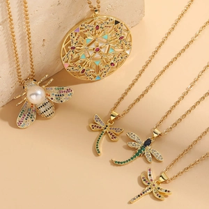 Dettaglio di collane placcate oro 14K con insetti in zircone e perle su supporto in pietra