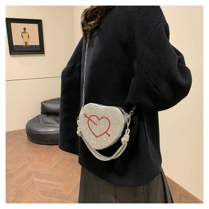 Dettaglio borsa a cuore con strass argentati e frange metalliche scintillanti sul lato