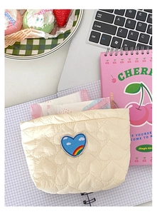 Dettaglio borsa trapuntata color crema a cuore con ricamo a nuvola arcobaleno
