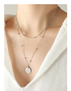 Detail of silver double-layered necklace with bead chain and evil eye coin pendant