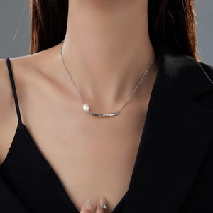 Detail of silver chain necklace with a pearl and engraved Freedom bar on a model