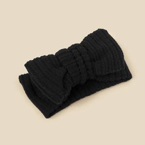 Detail showing the textured knit of a soft black elastic baby headband with a bow