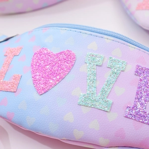 Close-up of pink glitter heart sequins and LOVE lettering detail on kids waist bag