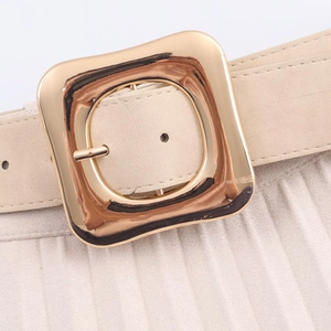 Détail de la jupe midi plissée beige avec une ceinture à boucle dorée élégante