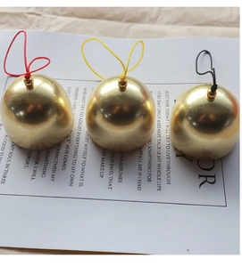Vue détaillée de trois pendentifs cloches en laiton doré mat avec des cordons de couleur