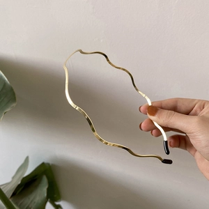Close-up of golden wavy metal headband with black protective tips for a sleek look