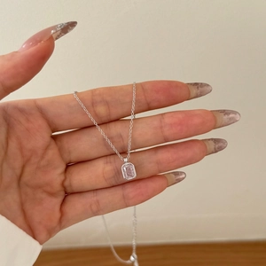 Detail of a thin silver necklace featuring a rectangular pink gemstone pendant