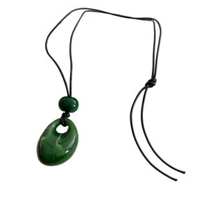 Vintage green acrylic teardrop pendant necklace with black cord on white background