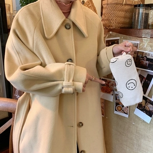 Detail of white corduroy pouch with black smiley face held by model in retro setting