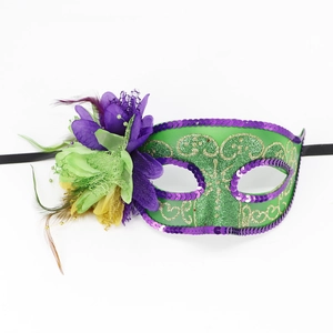 Close-up of green masquerade mask with purple sequins, silk flowers and feather detail