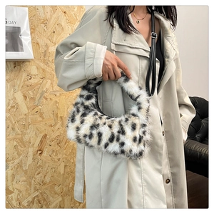 Detail of plush leopard print crescent bag with black leather strap worn with a beige coat