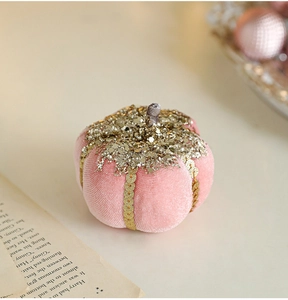 Close-up of pink velvet pumpkin with gold glitter detailing on vintage book pages