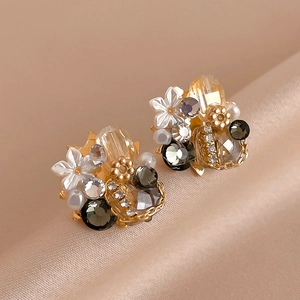 Macro shot of vintage floral earrings with crystals and pearls on champagne silk fabric